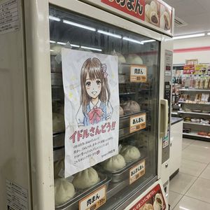 Take the image of the hand-drawn style idol character flyer and visually depict it as if it is adhered to a vending machine for steamed b...
