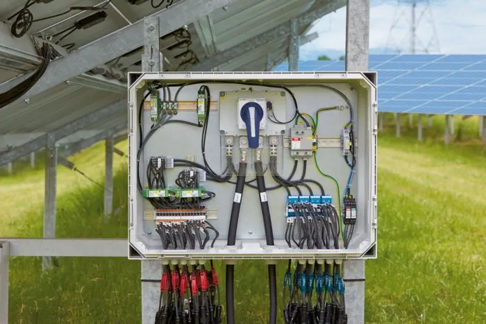 An open solar combiner box showing the internal wiring, busbars, and fuse holders.